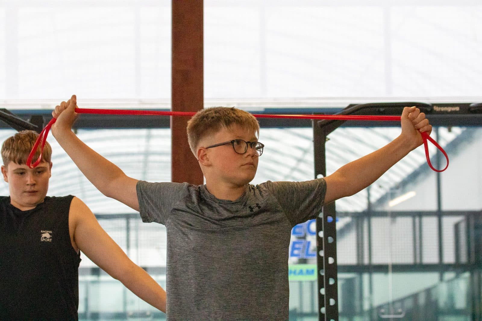 Two young athletes working through a banded pull at the rig